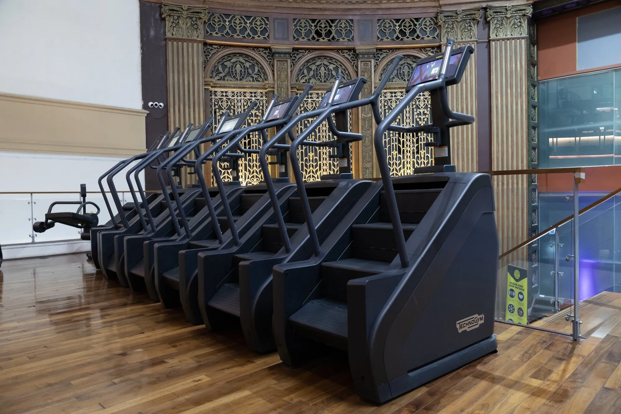 A row of stair climbers beside the cinema's gilded wall grilles
